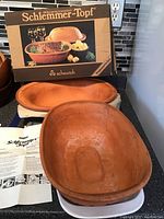 Photo shows the vintage Schlemmer-Topf clay roasting pot with lid, original box, and instruction papers laid out.