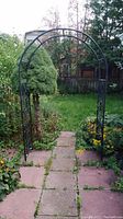 Metal garden arch trellis set up in a garden area showing two curved arches and black metal structure.