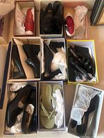Nine pairs of women's dress shoes shown mostly inside or partially inside original boxes with tissue paper. Includes black leather shoes, sandals, wedges, and slip-ons.
