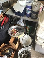 Photo showing canning pots, a steam vaporizer, and round roaster among other items on a shelf.