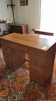 Full view of the vintage wooden desk showing the top surface and drawer fronts.