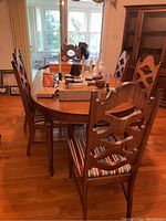 View of full dining table with six chairs, showing wooden carved backs and striped seats
