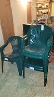 Six green plastic outdoor chairs shown stacked and standalone indoors to display condition and style.