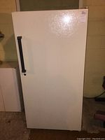Front view of the white Kenmore upright freezer, showing the door closed with black vertical handle.