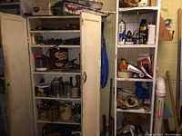 Overview of metal cabinets and shelves filled with paint cans, jars, trays, rollers, sanding materials, and other painting tools