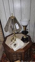 View of the full lot showing a white rotary phone, a brass lamp with a clear glass petal-shaped shade, and a black lamp with a brass base and white ribbed glass shade.