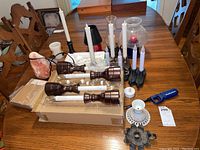 Full view of the salt lamp, multiple battery candles on wooden bases, white wax candles, black metal hurricane candle holders, a white ceramic candle holder, and blue lighter on table