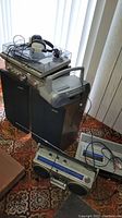 Full view of the lot showing Technics turntable on top of Kenwood speakers, vintage headphones on turntable, Sony CFD-S05 boombox on speakers, Sony CFS-400 boombox on floor, and Fisher VCR VHS recorder on floor with cords.