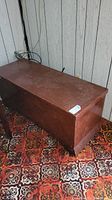 Image of vintage wooden Lane trunk showing exterior top and side surfaces with a reddish-brown finish and noticeable wear and scratches.