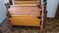 Two wooden twin bed frames with headboards and footboards stacked together showing the carved finials and turned posts.