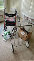 Overview of medical equipment including Drive F-22 hand walker, mobile wire cart, disposable gloves, masks, hand sanitizer on carpeted floor near a table and window.