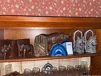 Bookends arranged on a wooden shelf showing all five sets including wooden rhinos, building bookends, blue geodes, large rhino figure and zebra-patterned pair