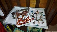 Photo showing three trays with various costume jewelry items including amber bead necklaces and bracelets, single earrings, and Irish coin bracelets and pins.