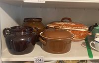 Photo of stoneware bean pots, ceramic covered bowl, and Romertoff clay baking dish grouped on shelf