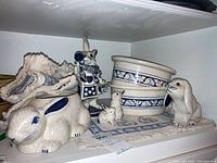 Overview photo of the rabbit patterned pottery bowls, figurines, and placemat arranged on a shelf.