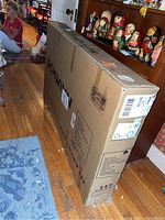 Boxed Schwinn Shuffle adult scooter in original packaging, standing upright indoors.