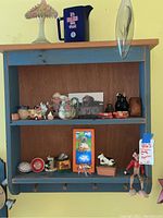 Full view of the wall shelf showing all items and peg hooks.