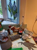 Overview of stained glass panels, wooden figurine, baseball cap, carved raccoon batula, glass bottle with red stopper, trinket box and other items