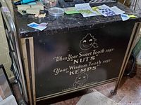 Full side and partial top view of the black enameled metal cabinet with white and gold printed branding and mascot.