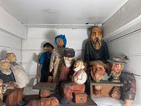 Overview of the entire wood carved figurine set displaying a variety of characters including a game table, old man and woman dolls, and carved stoppers.