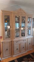 Front view of the two-piece bleached oak china cabinet with glass doors and wood lower cabinets.