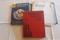 Three stamp albums side by side showing the covers: MINKUS United States Stamp Album, Crusader Stamp Album, and Modern Postage Stamp Album.