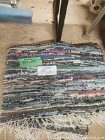 Folded colorful woven rag area rug with fringe and a label showing approximate size 40.5x59.5 inches.