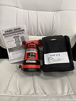 Black & Decker Crossfire Auto-Leveling Laser with instruction manual and black carrying case displayed on white chair.