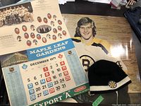 Photo showing vintage 1971 Maple Leaf Gardens playoff schedule with team photos and dates along with a knit Boston Bruins hat.