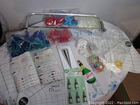 Overview of assorted cake decorating tools including piping tips, various molds, and colorful decorations laid out on a table with a measuring guide mat beneath.