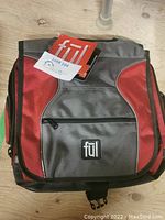 Closed Ful shoulder bag showing red and gray color blocking with front zippered pocket and Ful logo patch.