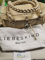 Beige Liebeskind Berlin handbag resting on white fabric cover bag with 'Liebeskind Berlin' printed text.
