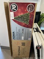 Box showing front of the NOMA 6.5 feet Christmas tree with image of fully lit tree and product details.