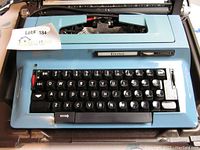 Front view of blue Electra typewriter showing keyboard, brand label, and model.