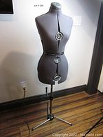 Front view of gray fabric dress form mounted on chrome tripod stand showing overall condition and structure