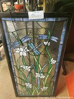 Full view of stained glass panel in black wooden frame