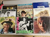 Top view of a selection of vinyl records featuring classic artists such as Elvis Presley, Cliff Richard, Corey Hart, John Denver, and Anne Murray with album cover visible