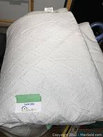 Folded white king size comforter with a visible diamond textured pattern on surface.