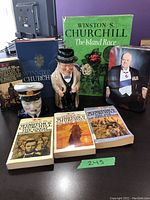All items shown including books, two porcelain figurines, and a metal tin with Churchill image