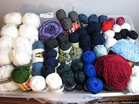 Full overview of the yarn skeins in various colors and brands arranged in a plastic bin