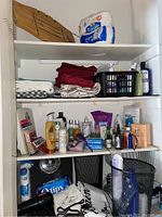 Cupboard shelves showing assorted beauty supplies, bath products, folded linens, and some toiletries.