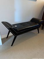Bench front and side view showing tufted seat, curved arms, nailhead trim and splayed legs
