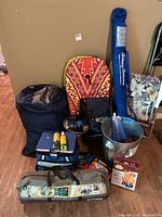 Photo showing entire lot including tent bag, cooler, sleeping bag, umbrella, paddle boards, chair, bucket, and miscellaneous items