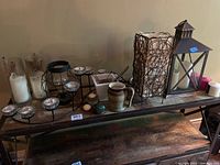 Wide view of the collection including candleholders, decorative items, lamp, and lantern on a wooden shelf