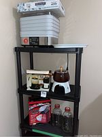 Full shelf setup showing all items: Hamilton Beach food dehydrator, fondue set, milk bottles, popcorn maker in box, and serving tray on top shelf.