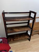 Full view of the wooden folding bookcase with three shelves, showing the dark wood and folding side panels.