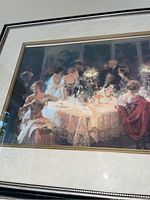 Close-up of gold-framed print showing classical dining scene with multiple figures, signed A. Renoir, and signature visible along bottom edge