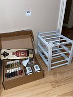 Lot showing gin making kit with botanicals and jiggers alongside Molson Export bottle opener and a small whitewashed wooden shelf or wine rack on floor.