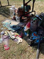 Photo showing a collection of garden ornaments including metal bird shaped decor, a garden gnome, an owl ornament, a wooden bird house, and a white lantern.