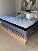 Grey tufted king mattress on split boxspring with wooden platform